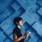 woman holding phone in front of blue wall with square design